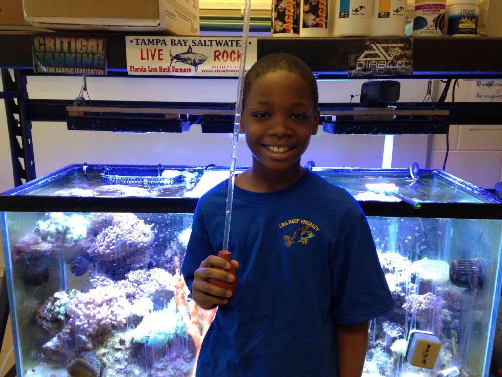 Leon stands in front of the tank that he cares for in his classroom.