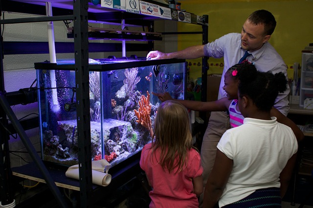 The author shown discussing marine ecology with third grade students using a tank designed to be an instructional tool.