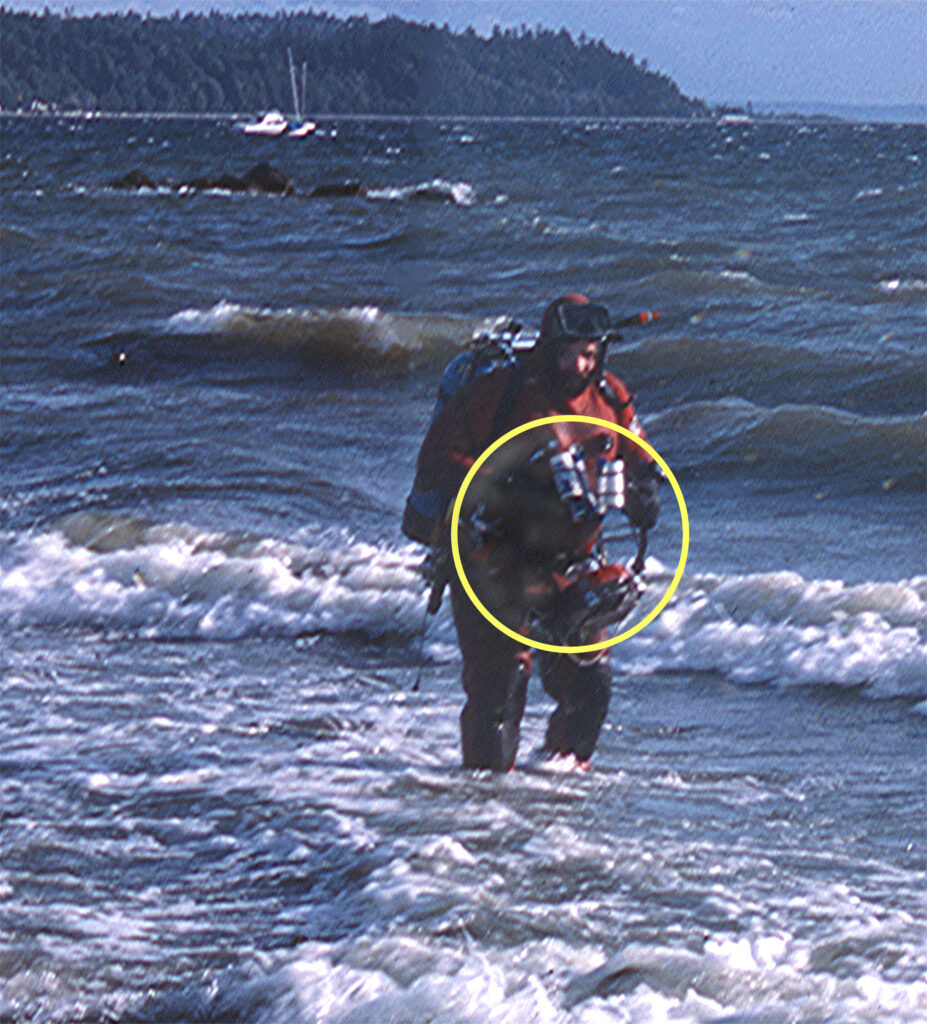 Ron Shimek surfacing after a dive to photograph animals in a Puget Sound Sea Pen Bed. The camera apparatus is circled.