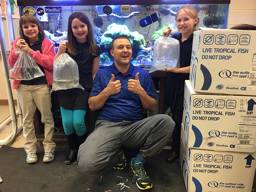 Brandon Rutherford (center right) and students pose with clownfish ready to ship to Quality Marine.