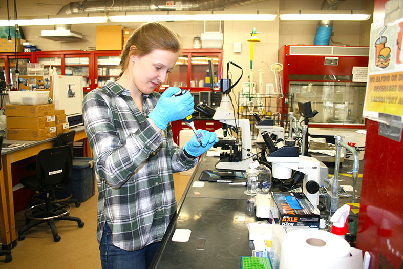 Drawing plasma from a blood sample, Sara Hunt prepares a slide to examine the specimen under a microscope.